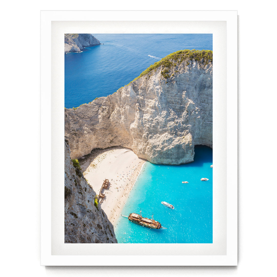 a picturesque coastal scene with a rocky cliff overlooking a turquoise sea dotted with boats.