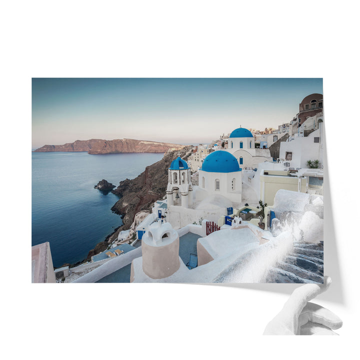 a picturesque coastal town with white buildings and blue domes overlooking the ocean.