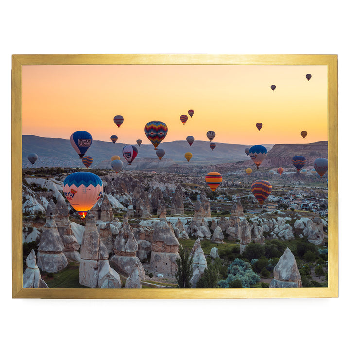 a breathtaking scene of hot air balloons floating over a mountainous landscape at sunset.