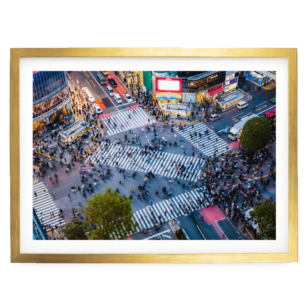 a busy city intersection with a large crowd of people crossing the street, surrounded by tall buildings and illuminated by colorful lights.