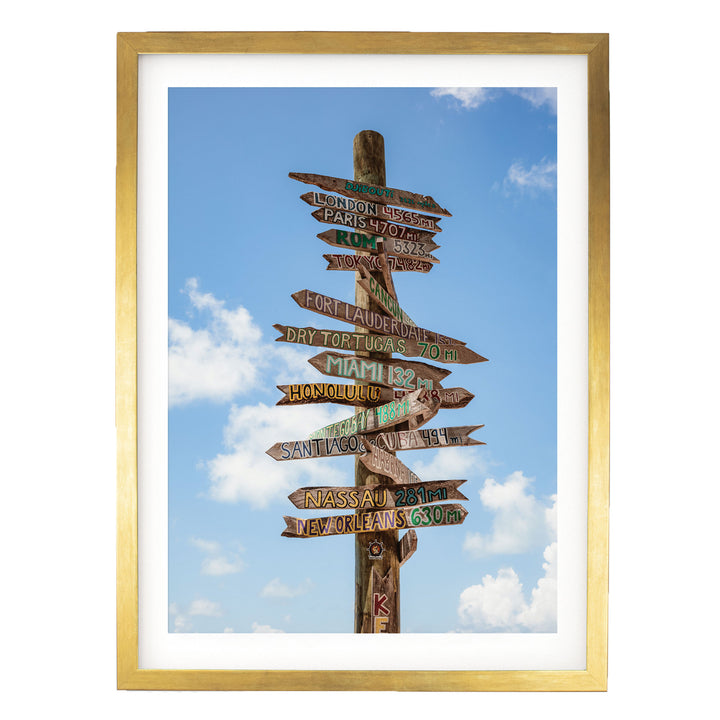 a wooden signpost with multiple directional signs pointing in various directions, against a backdrop of a blue sky with clouds.