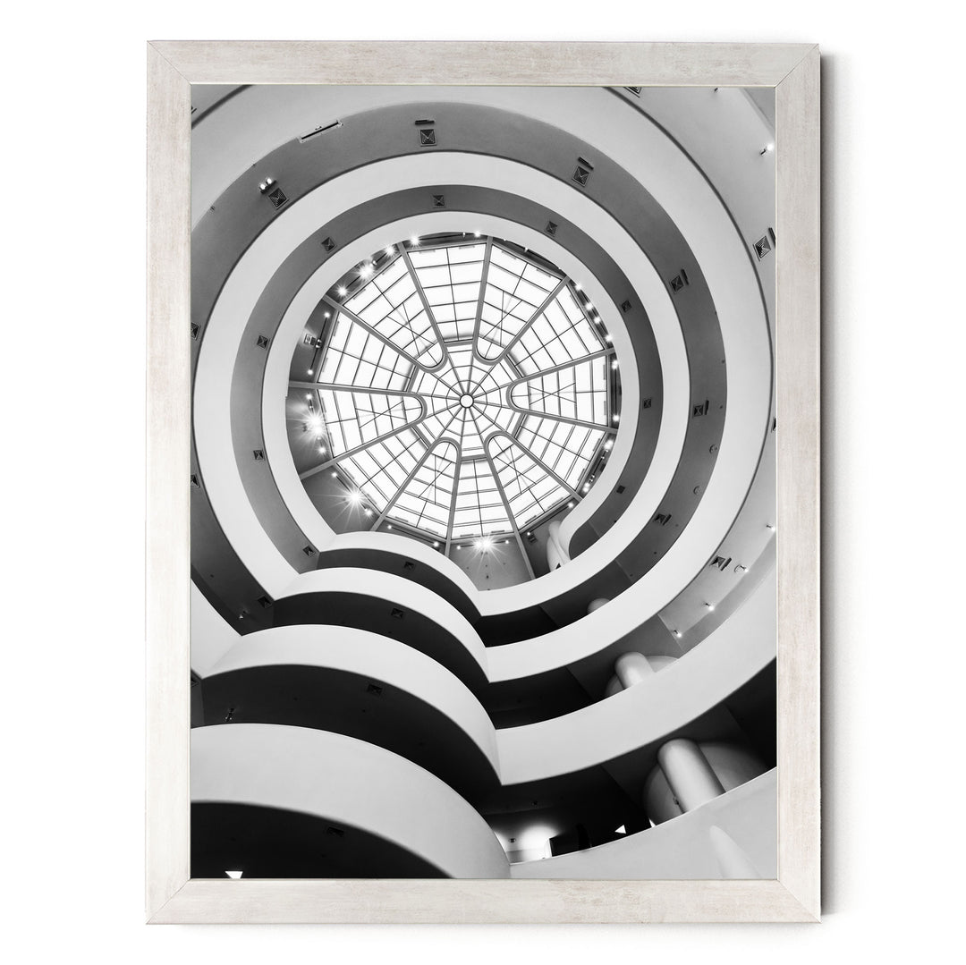 A black and white photograph of a spiral staircase with a large circular glass dome at the top, creating a striking architectural design.