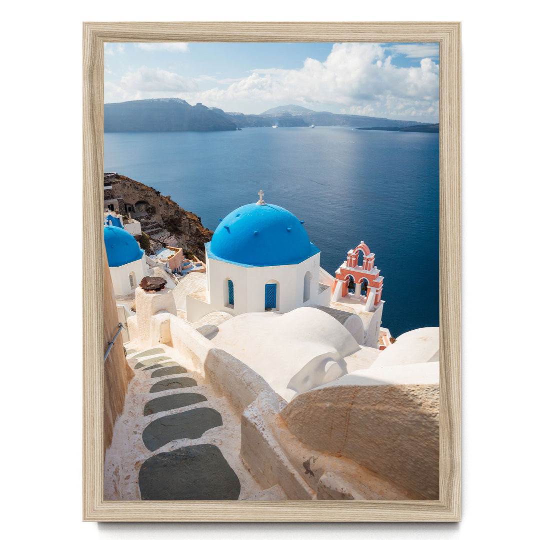 a picturesque view of a Greek island with white buildings and blue domes, overlooking the deep blue sea.