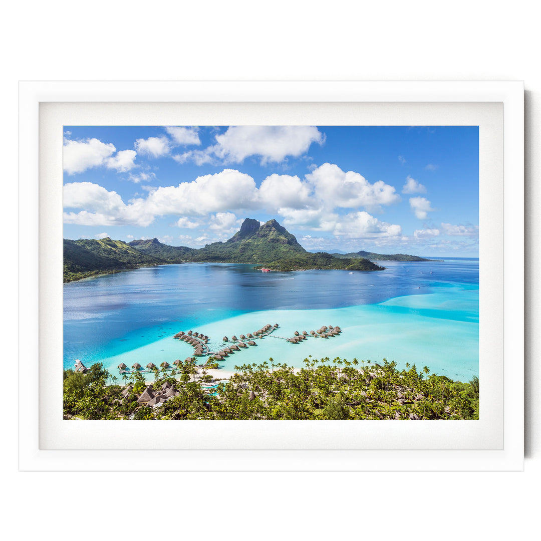 A picturesque tropical island with crystal clear turquoise waters, lush green vegetation, and a mountainous backdrop. The island is dotted with several small islands and is surrounded by a vast expanse of water. The sky is a beautiful shade of blue with fluffy white clouds. The image is framed and appears to be a collage of multiple images, creating a harmonious and visually appealing composition.