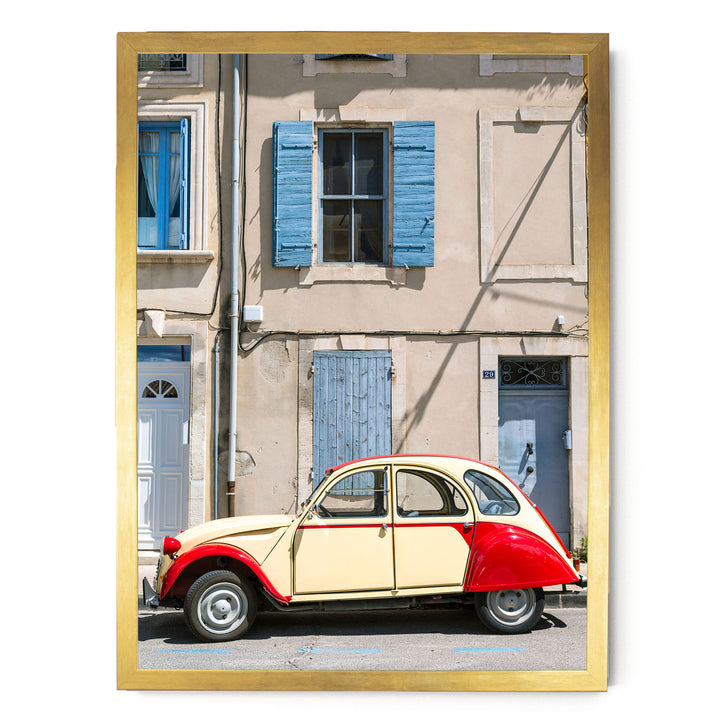 A vintage red and cream car is parked in front of a building with blue shutters and a white door.