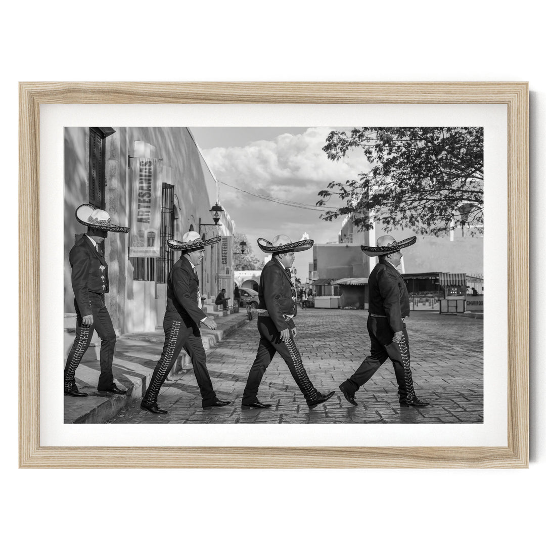 A black and white photograph of a group of men wearing sombreros walking down a street.