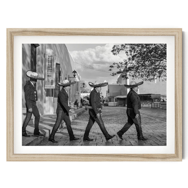 A black and white photograph of a group of men wearing sombreros walking down a street.