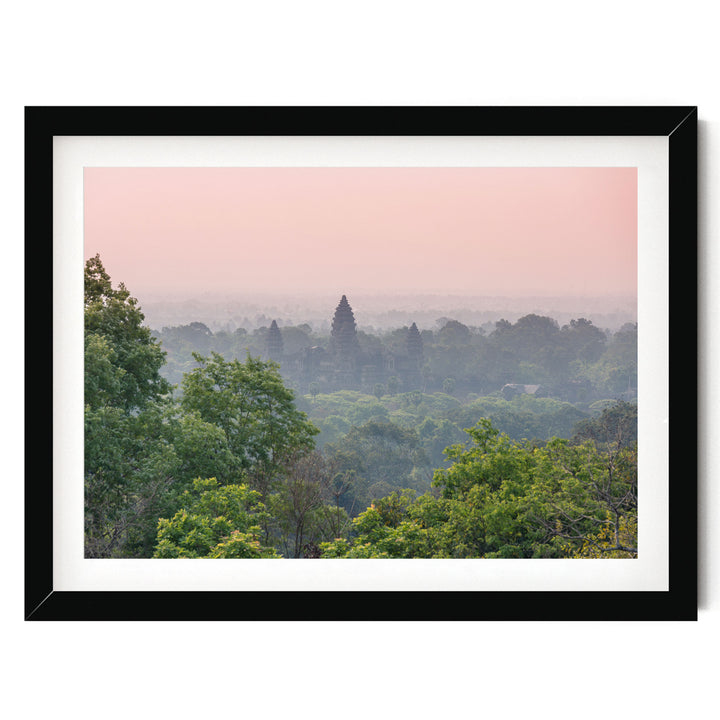A framed photograph depicting a lush, green forest with a hazy, pink sky in the background.