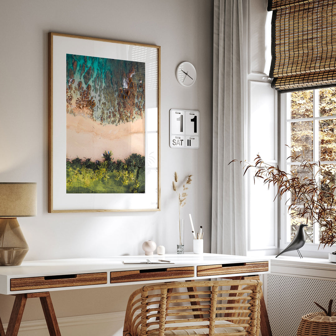 a modern and minimalist living space with a large framed landscape painting hanging on the wall above a white desk. The desk has a lamp and a plant on it, creating a cozy and inviting atmosphere.