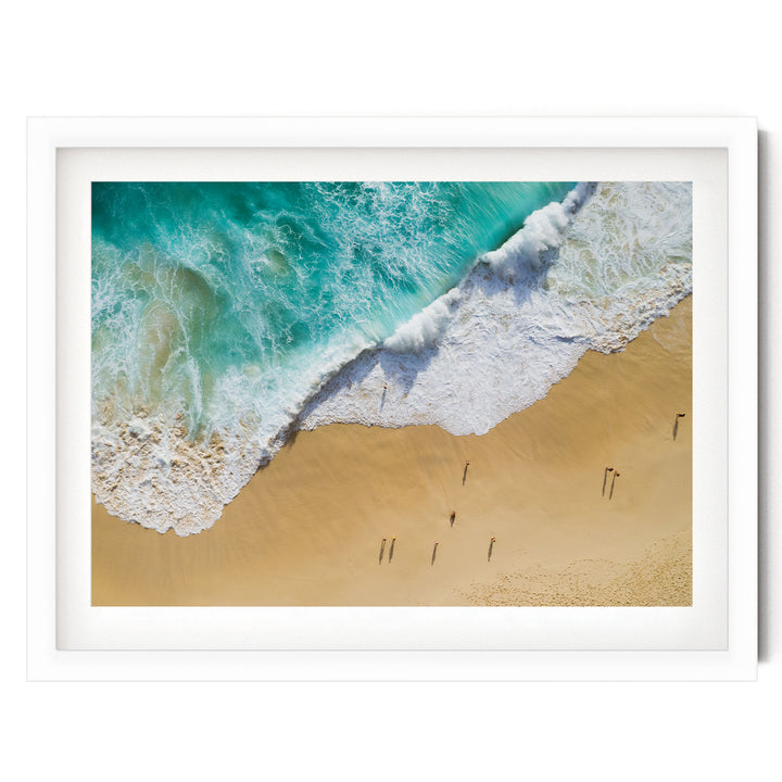 a serene beach scene with a clear blue sky, turquoise water, and a sandy shoreline. Several people can be seen walking along the beach, enjoying the beautiful landscape.