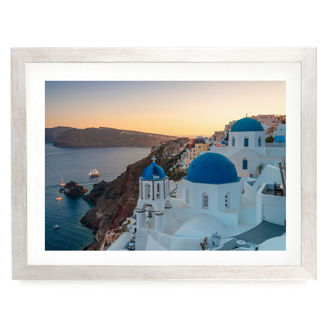 a picturesque coastal town with white buildings and blue domes, overlooking the ocean.