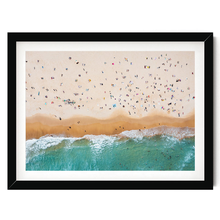 a crowded beach with many people enjoying the sunny day, with waves crashing onto the shore.