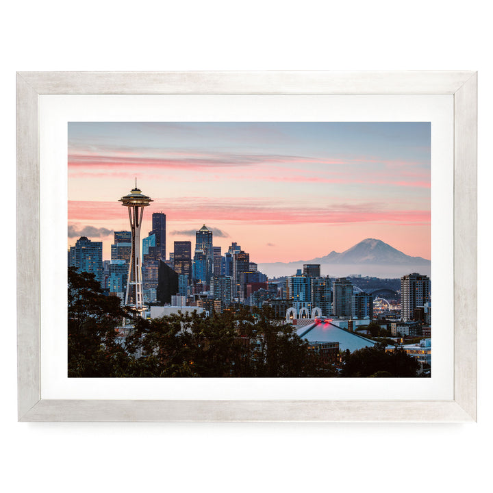 a cityscape with a tall tower, likely a landmark, in the foreground, surrounded by a mix of modern and older buildings. The sky above is a beautiful gradient of pink and orange, creating a stunning backdrop for the city skyline.