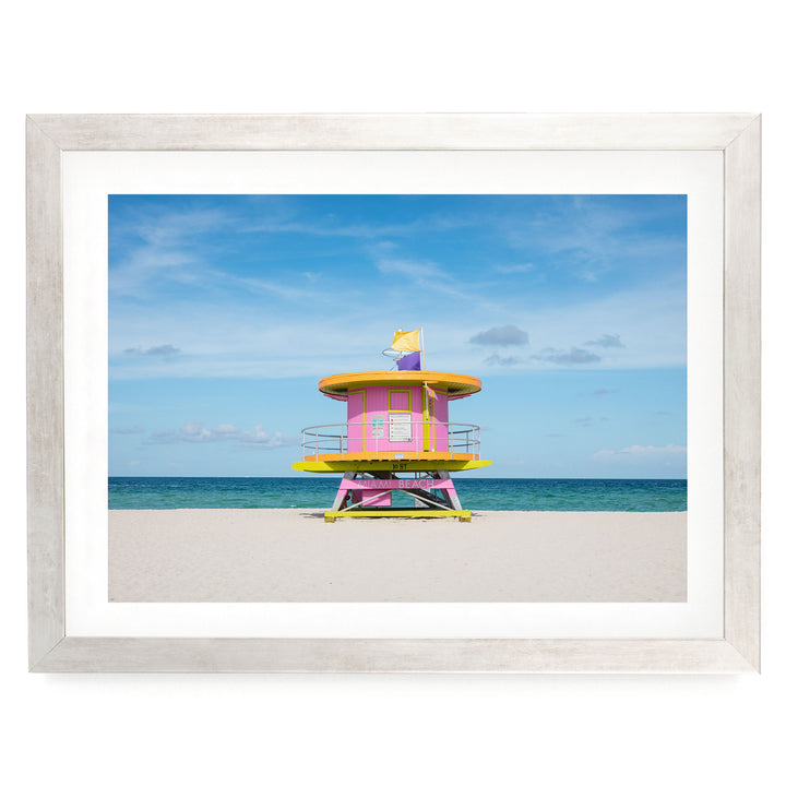 A colorful lifeguard tower stands on a sandy beach, overlooking the ocean.