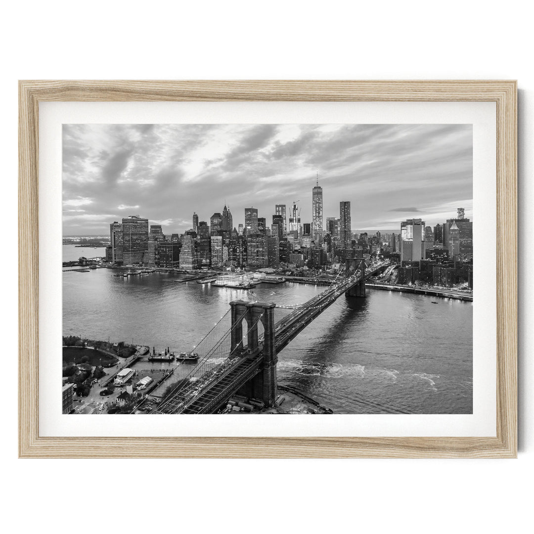 A black and white photograph of the New York City skyline, featuring the Brooklyn Bridge and the surrounding cityscape.
