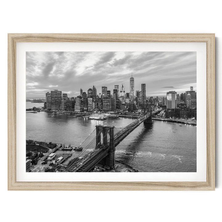 A black and white photograph of the New York City skyline, featuring the Brooklyn Bridge and the surrounding cityscape.