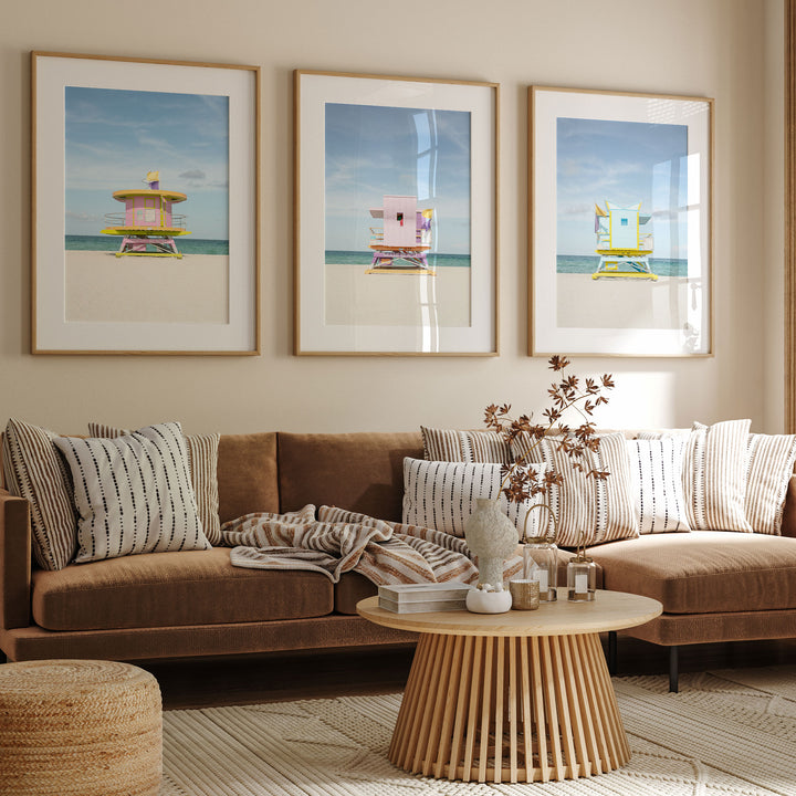a cozy living room with a brown sofa, a wooden coffee table, and three framed beach lifeguard towers on the wall.