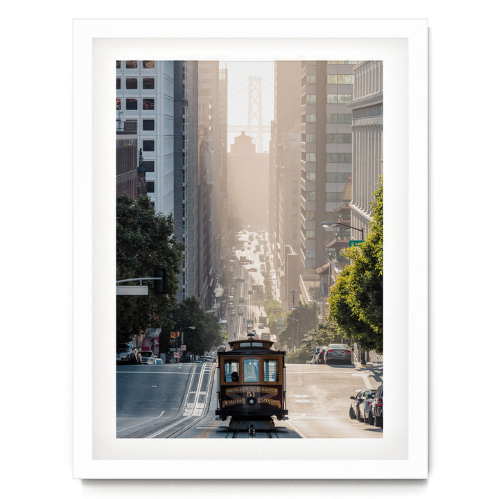 A trolley car travels down a busy city street, surrounded by tall buildings and lush green trees.