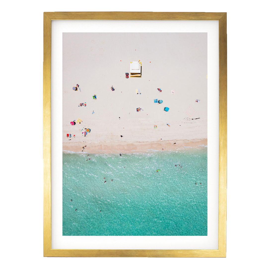 The image is a framed aerial view of a beach scene with people enjoying the sun and water.