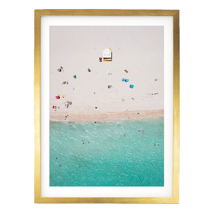 The image is a framed aerial view of a beach scene with people enjoying the sun and water.