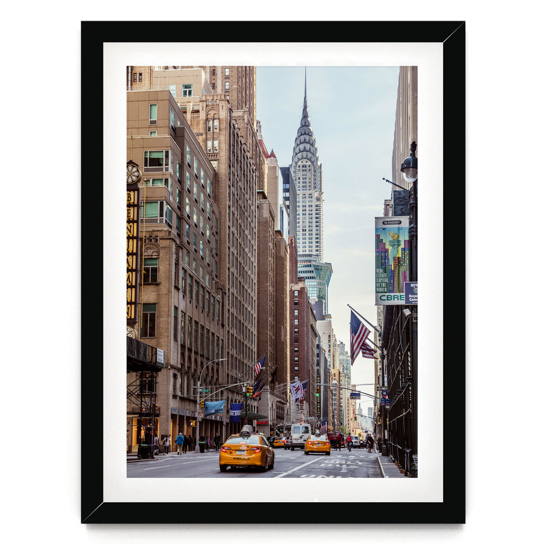 A bustling city street with tall buildings, including the iconic Chrysler Building, and yellow taxis driving down the road.