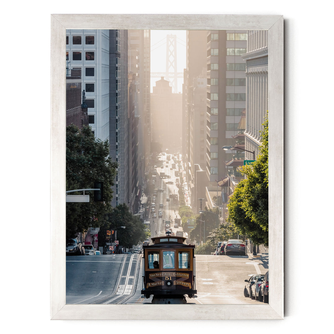 A cable car travels down a busy street in San Francisco, surrounded by tall buildings and lush green trees.