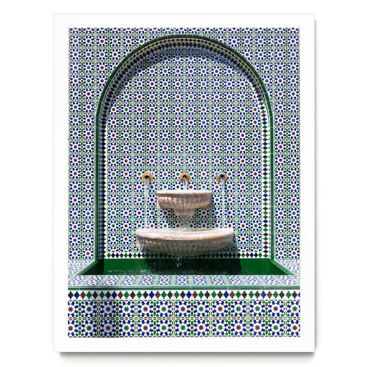 a decorative fountain with a green border and a tiled wall behind it.