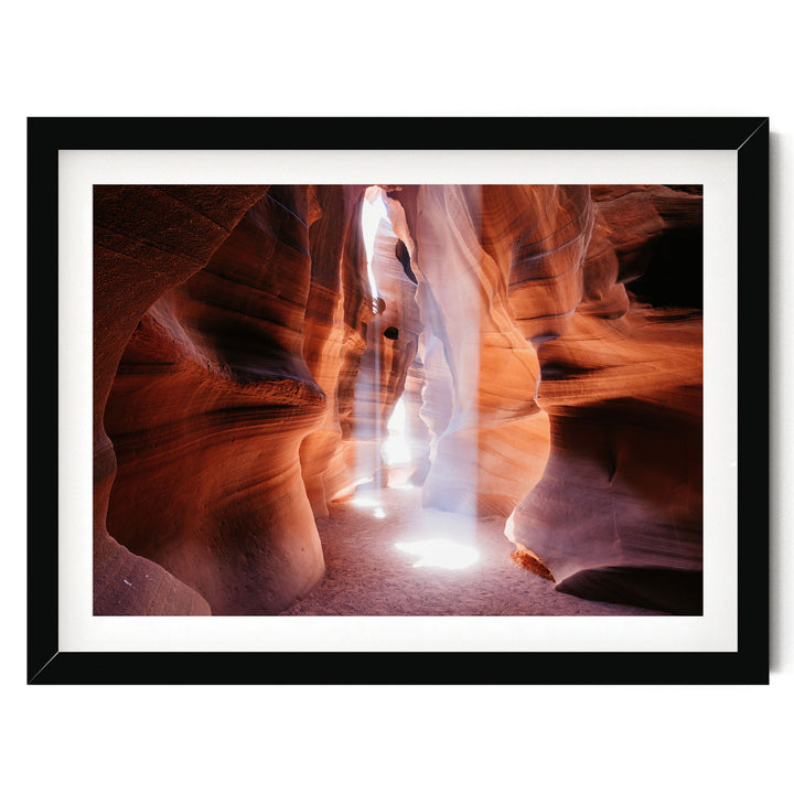 A framed photograph depicting a narrow, winding path through a canyon with a bright light shining through the rock formations.