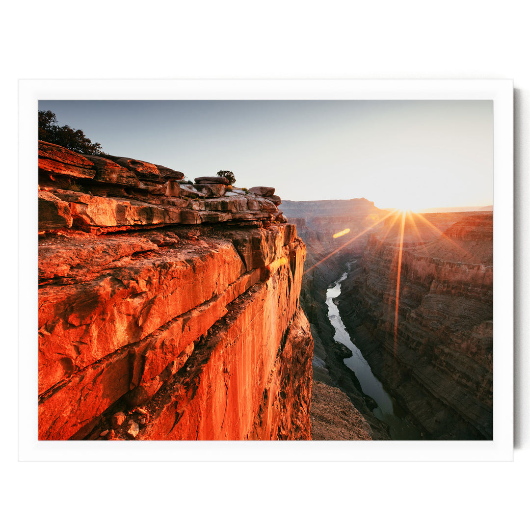 A breathtaking view of a canyon at sunset, with the sun's rays shining down on the rugged, rocky cliffs and the winding river below.
