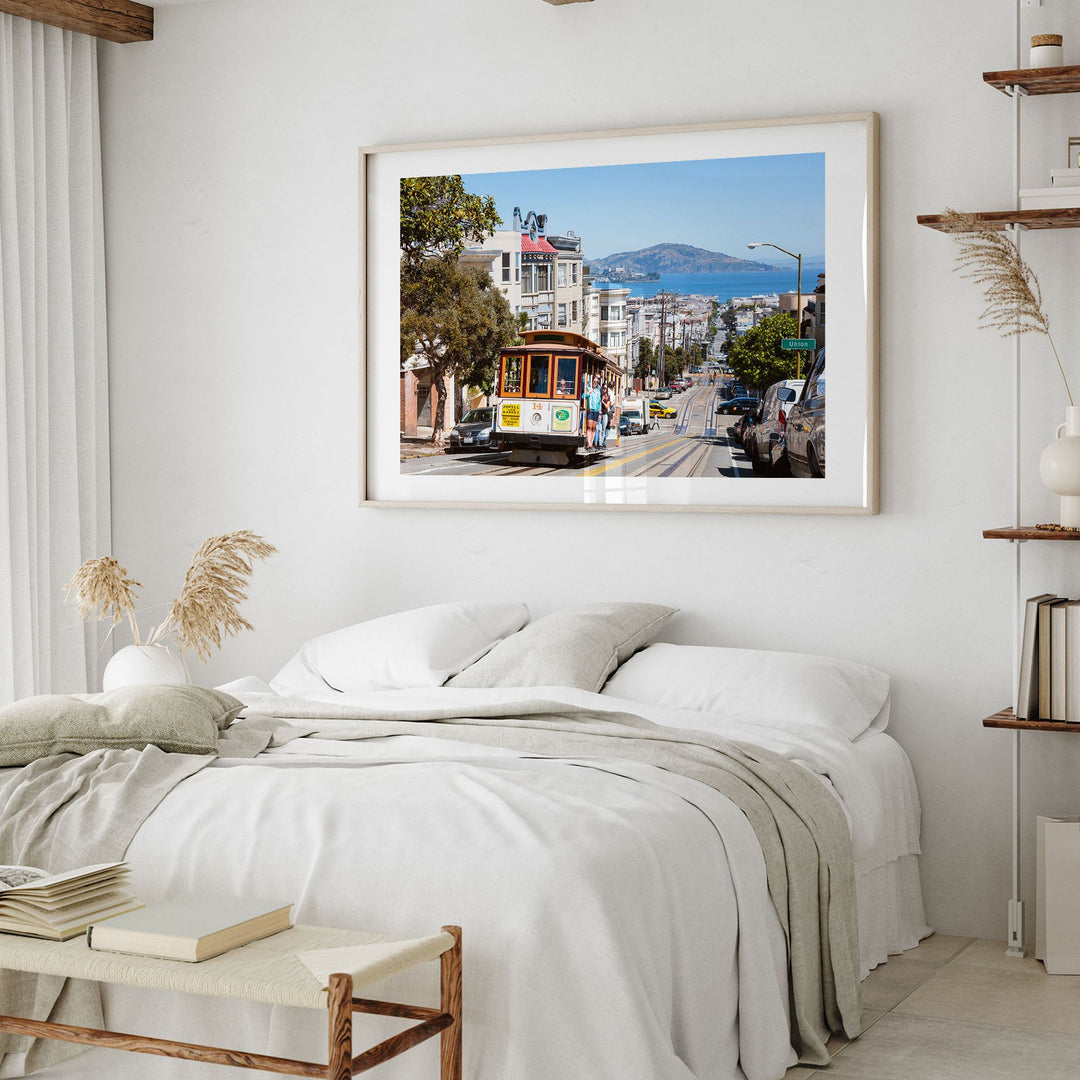 a bedroom with a large framed picture of a trolley car on the wall above a bed with white bedding.