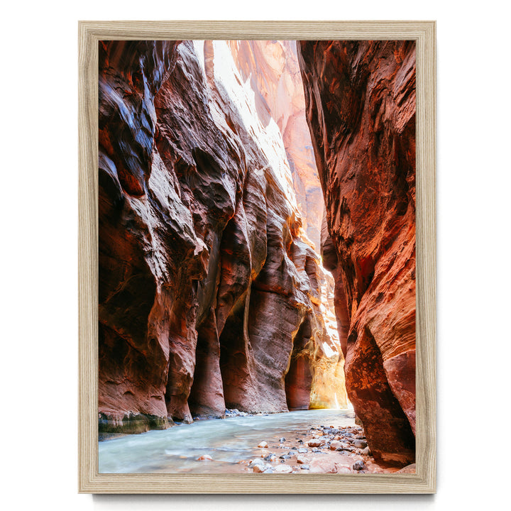 A framed photograph depicting a narrow, winding river flowing through a canyon with towering red rock walls on either side.