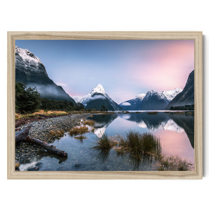a serene landscape with snow-capped mountains reflected in a calm lake, surrounded by lush vegetation and a wooden frame.