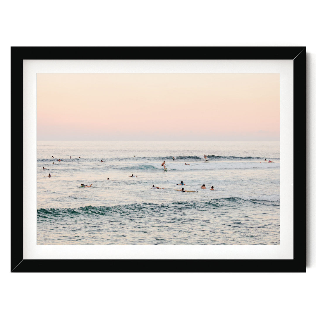 A group of people enjoying a day at the beach, with some of them surfing on the waves.
