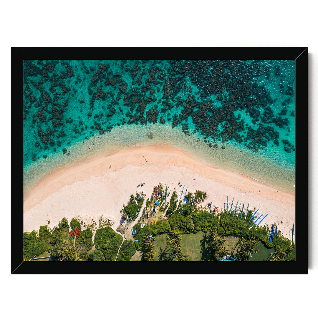 The image is an aerial view of a tropical beach with crystal clear turquoise waters, sandy shores, and lush vegetation surrounding the area.