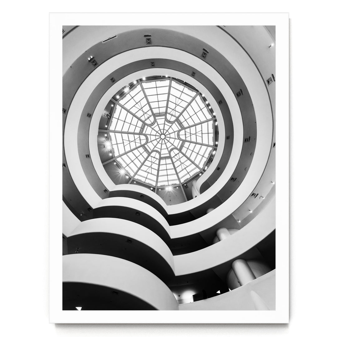 A black and white photograph of a modern, multi-level building with a large, circular glass dome at the center, creating a striking visual effect.