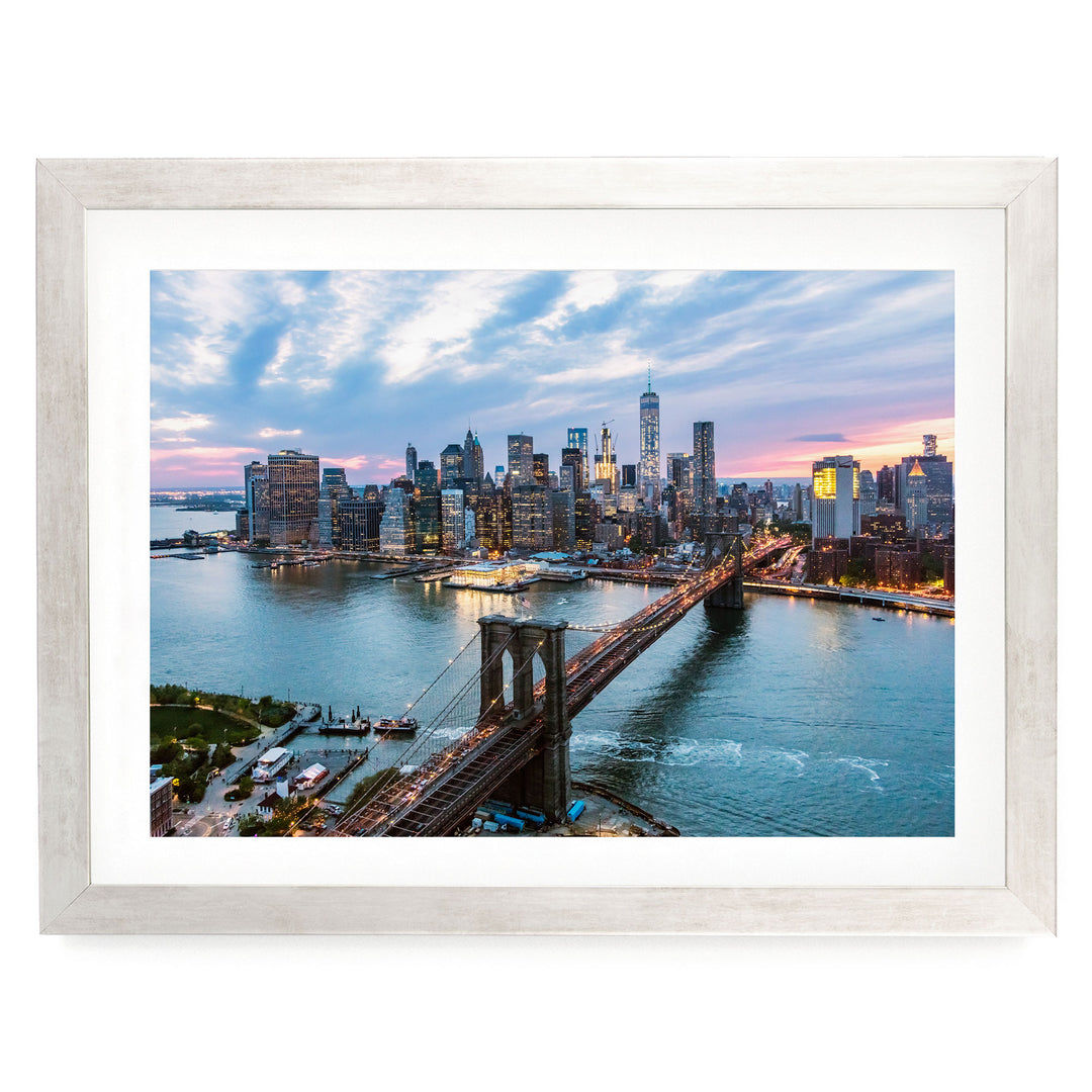 a cityscape with a bridge spanning a river, surrounded by tall buildings and a colorful sunset sky.