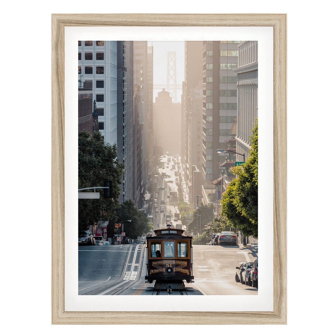 A trolley car travels down a busy city street, surrounded by tall buildings and lush green trees.