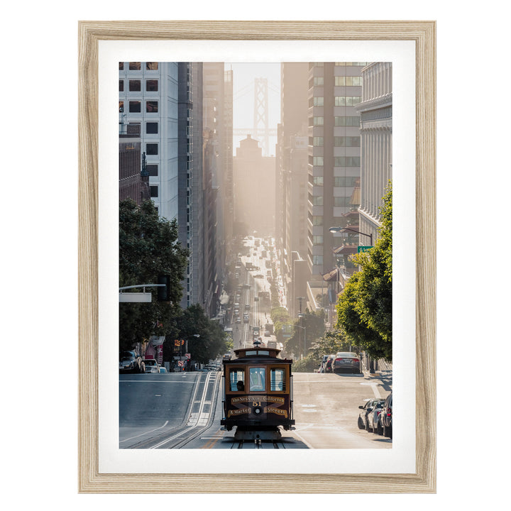 A trolley car travels down a busy city street, surrounded by tall buildings and lush green trees.