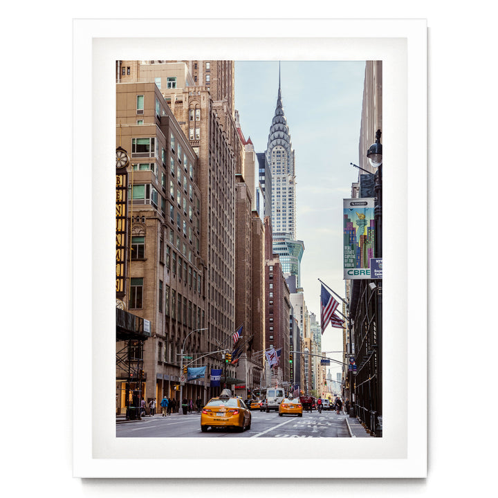 A bustling city street with tall buildings, including the iconic Chrysler Building, and yellow taxis driving down the road.