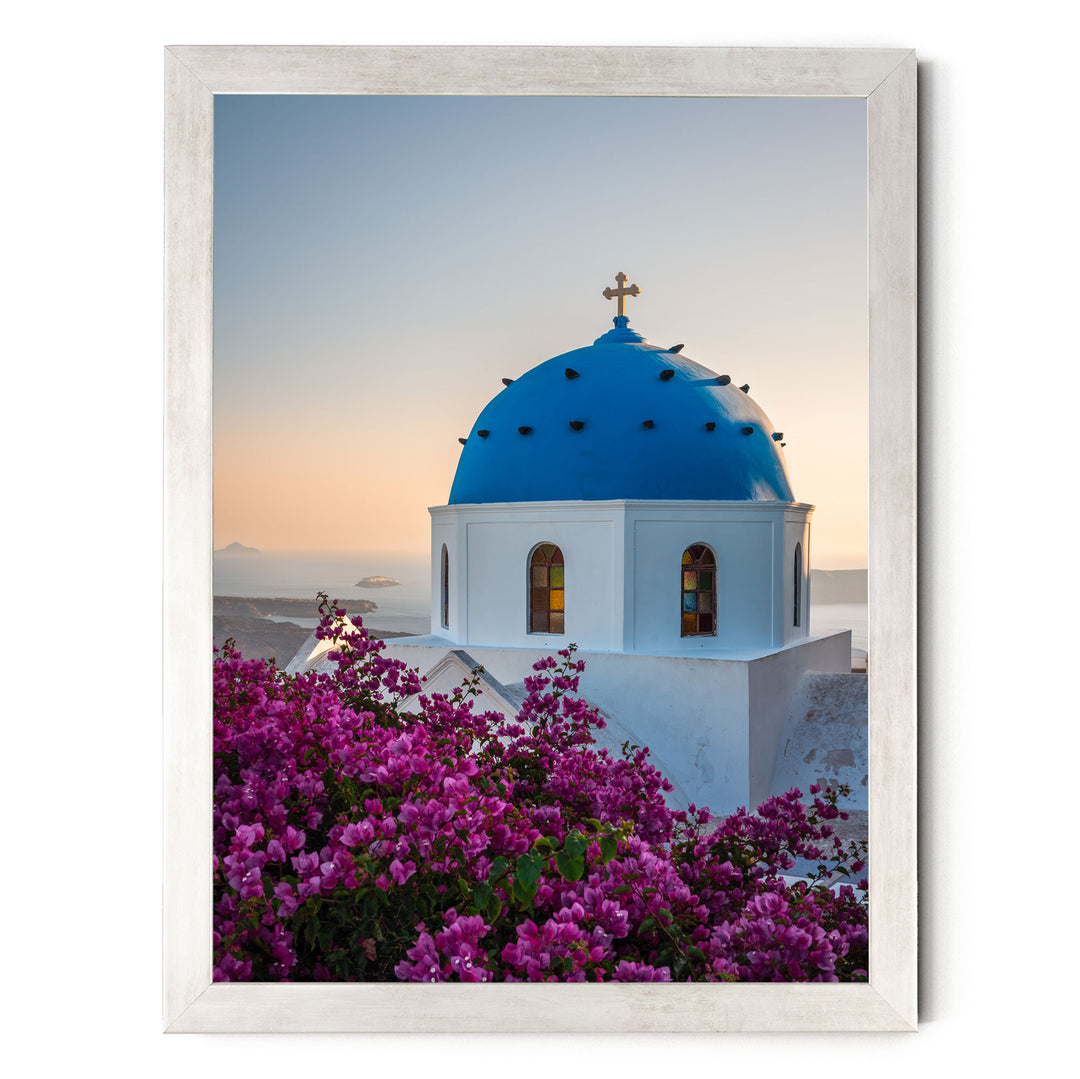 a blue domed church with a cross on top, surrounded by a vibrant display of purple flowers.