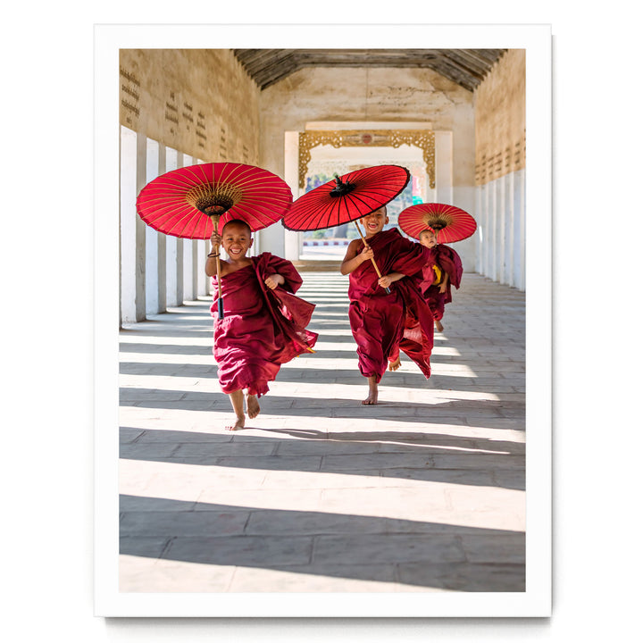 Three monks in red robes walking down a hallway, each holding a red umbrella.