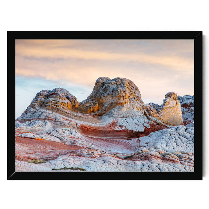 A striking landscape with a mountain range in the background, featuring a mix of orange, red, and white rock formations. The sky above is a beautiful gradient of orange and pink, creating a dramatic backdrop for the natural scenery.