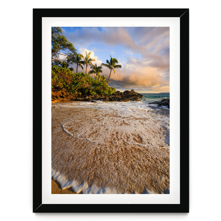 A framed photograph depicting a serene beach scene with palm trees, crashing waves, and a colorful sky at sunset.