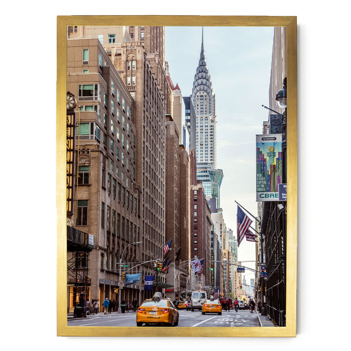 a busy city street with tall buildings, including the iconic Chrysler Building, and yellow taxis driving down the street.