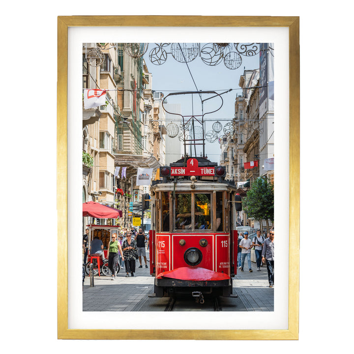 A red trolley car is traveling down a busy street in Istanbul, Turkey, surrounded by pedestrians and buildings.