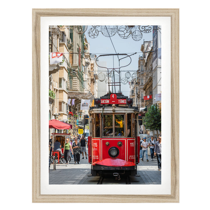 A red trolley car is traveling down a busy street in Istanbul, Turkey, surrounded by pedestrians and buildings.