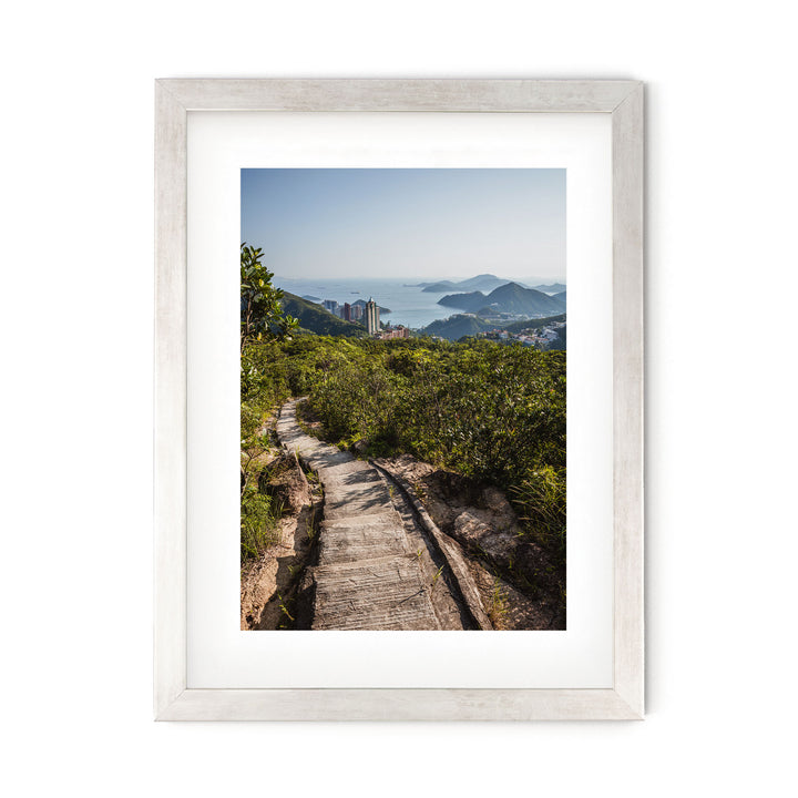 a framed photograph of a path leading to a city