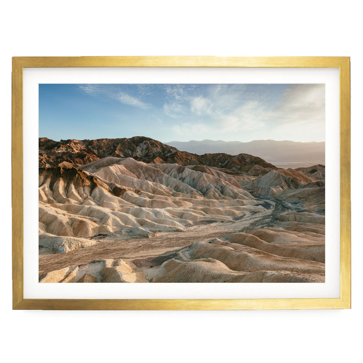 a vast, rugged landscape with rolling hills and mountains in the background, set against a clear blue sky.