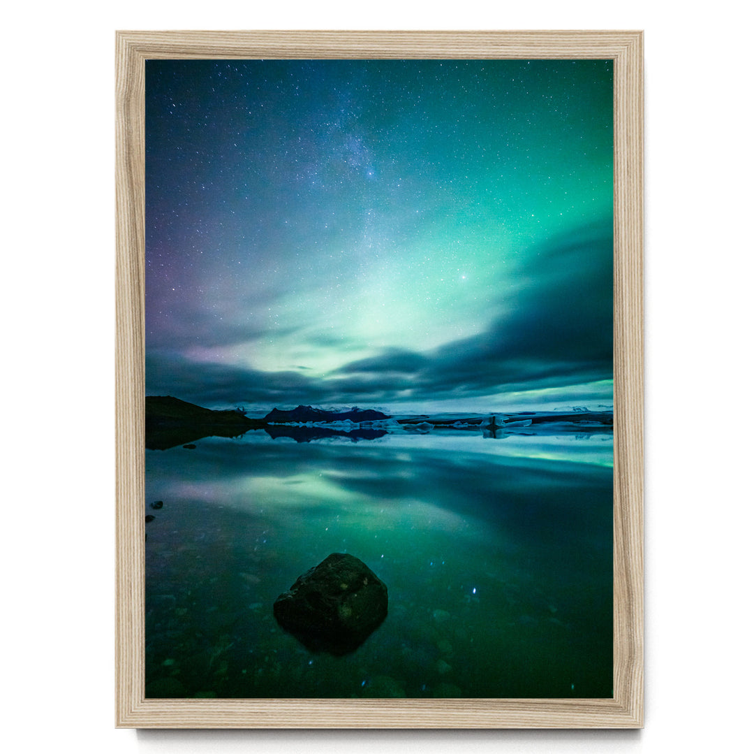 a serene night scene with a starry sky reflected in a calm body of water, surrounded by mountains.