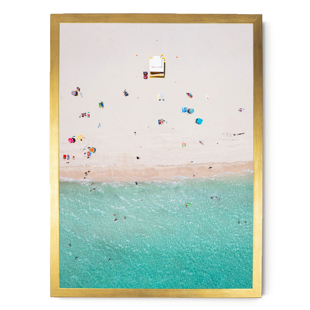 The image is a framed aerial view of a beach scene with people enjoying the water and sand.
